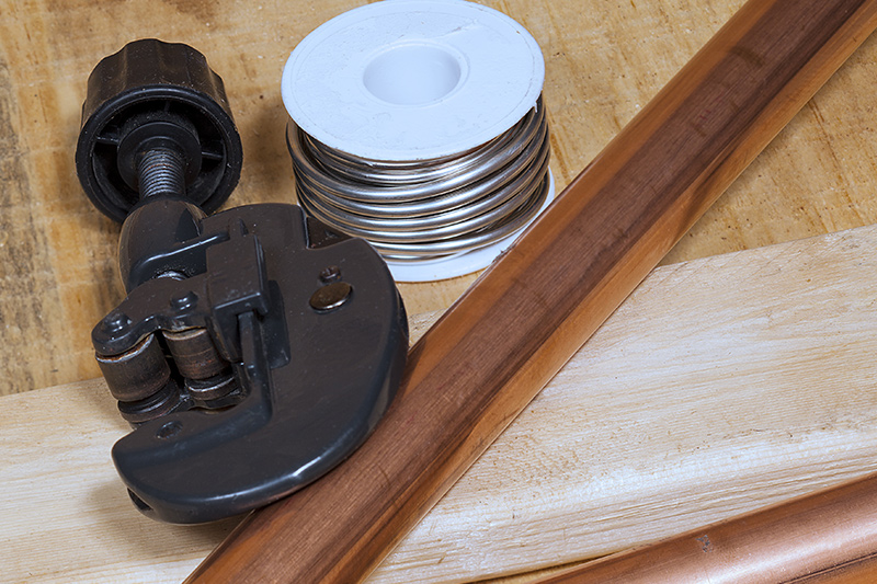 Image of a pipe cutter next to a copper pipe