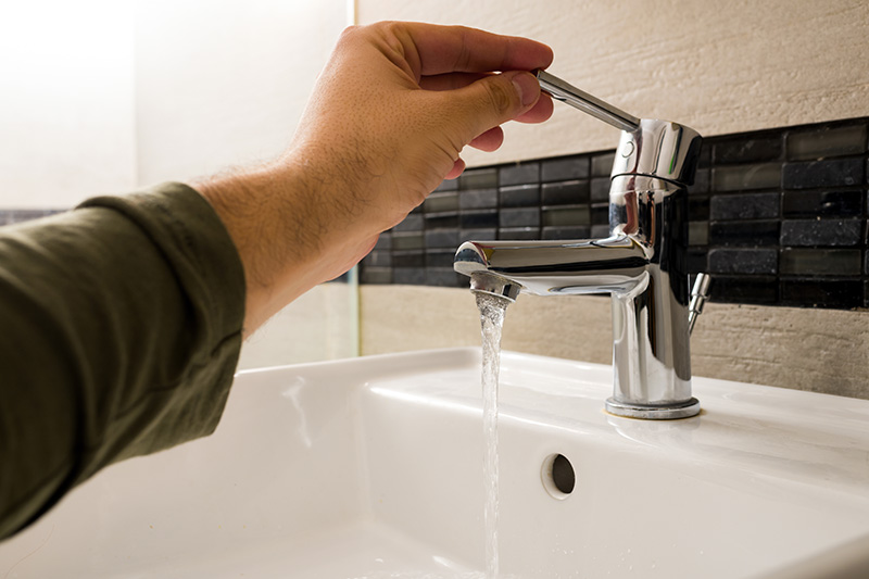 photo of man turning on bathroomm faucet