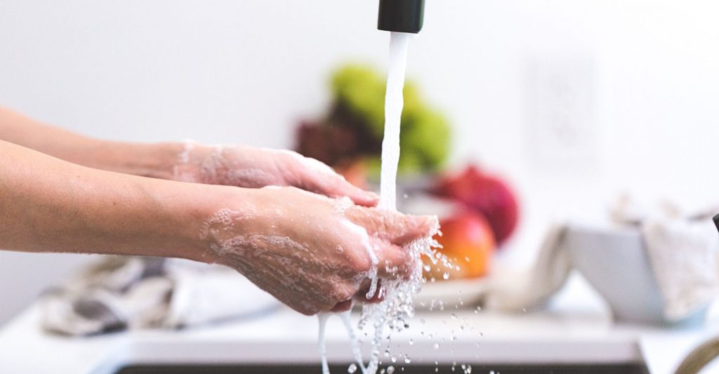 A person washing their hands in the sink.